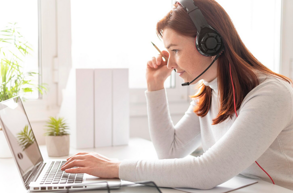 une page web s'affiche sur l'écran d'un ordinateur portable posé sur une table en bois. Un fauteuil, une table basse et une plante an arrière-plan.